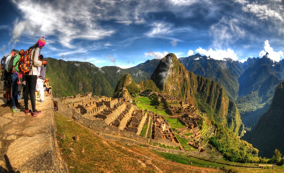 HDR image of tourists observing the wonder of Machu Picchu, the lost city of the Inca near Cusco, Peru.